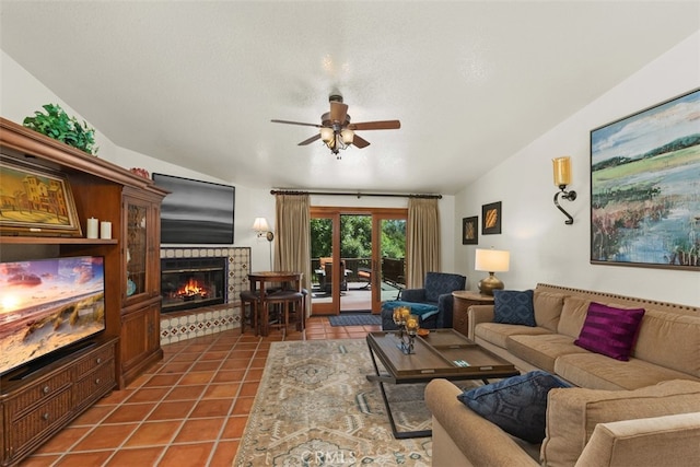 living room featuring lofted ceiling, ceiling fan, a textured ceiling, a tile fireplace, and tile patterned floors