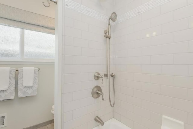 bathroom with toilet and tiled shower / bath