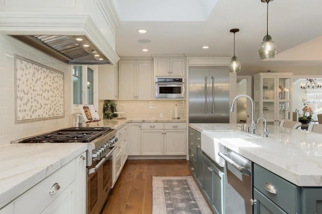 kitchen with high end appliances, decorative backsplash, white cabinets, and pendant lighting