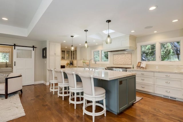 kitchen with a spacious island, a barn door, decorative light fixtures, and plenty of natural light