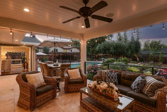 patio terrace at dusk with ceiling fan, a fenced in pool, and an outdoor living space