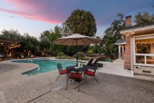 pool at dusk with a patio area