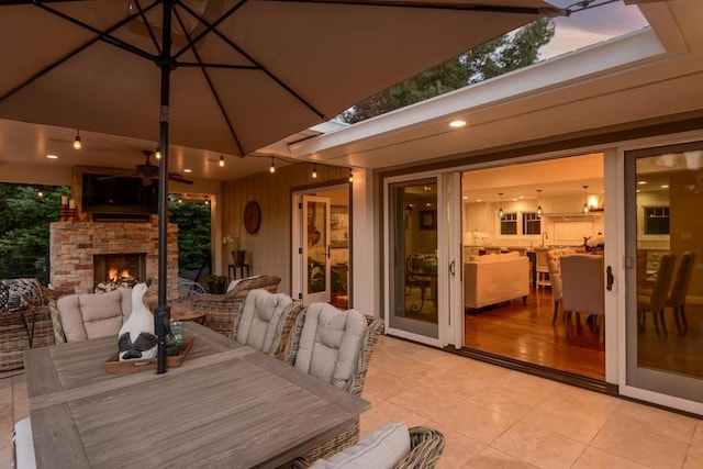 patio terrace at dusk featuring an outdoor stone fireplace