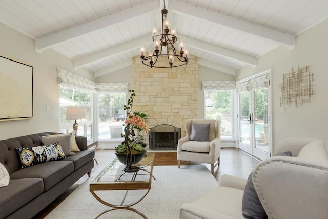 living room with hardwood / wood-style flooring, an inviting chandelier, vaulted ceiling with beams, and a stone fireplace