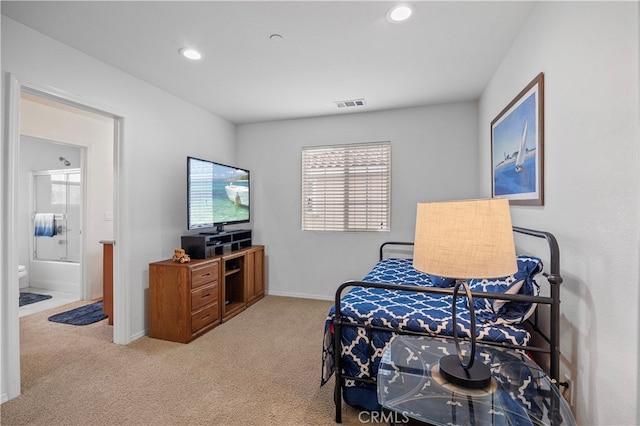 bedroom featuring ensuite bath and light colored carpet