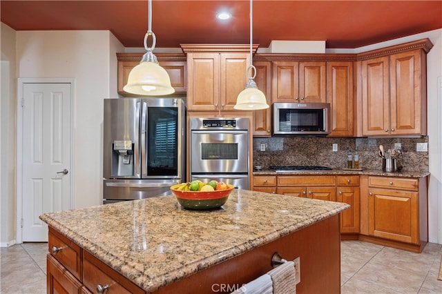 kitchen with appliances with stainless steel finishes, light stone countertops, a center island, and pendant lighting