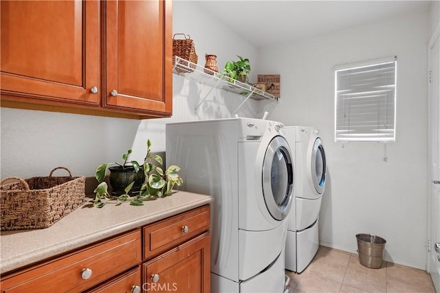 laundry area featuring washing machine and dryer, light tile patterned flooring, and cabinet space