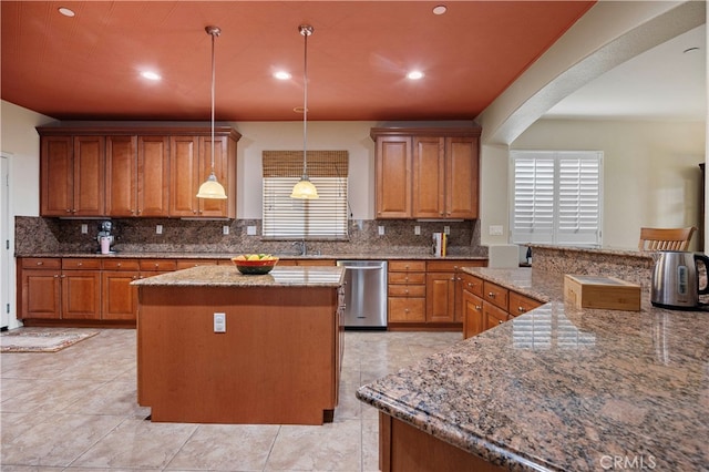 kitchen with stainless steel dishwasher, a center island, hanging light fixtures, and light stone countertops