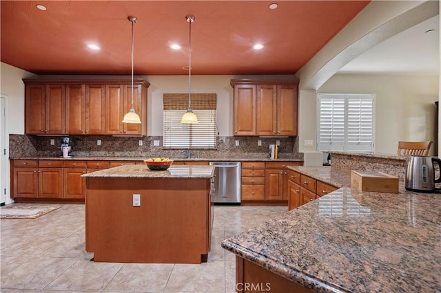 kitchen with a center island, plenty of natural light, stainless steel dishwasher, and brown cabinetry