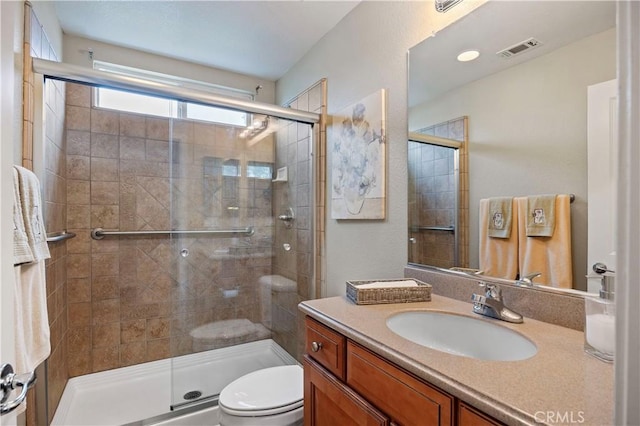 full bathroom featuring toilet, visible vents, vanity, and a stall shower