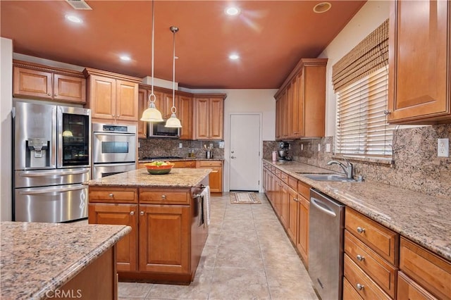 kitchen with a sink, light stone countertops, a kitchen island, tasteful backsplash, and appliances with stainless steel finishes