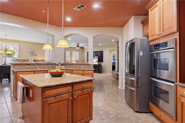 kitchen featuring a kitchen island, appliances with stainless steel finishes, pendant lighting, and ceiling fan