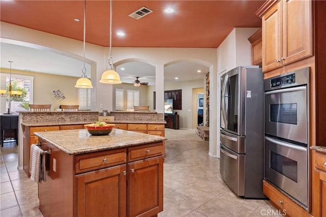 kitchen with light tile patterned flooring, a center island, stainless steel appliances, and visible vents