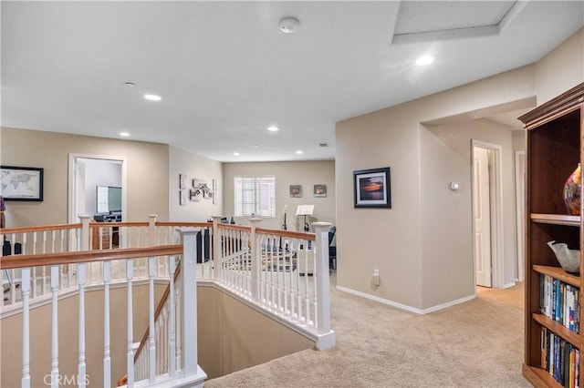 corridor featuring an upstairs landing, attic access, carpet floors, baseboards, and recessed lighting