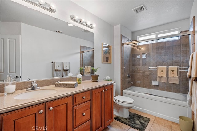 full bathroom with shower / bath combination with glass door, tile patterned floors, toilet, vanity, and a textured ceiling