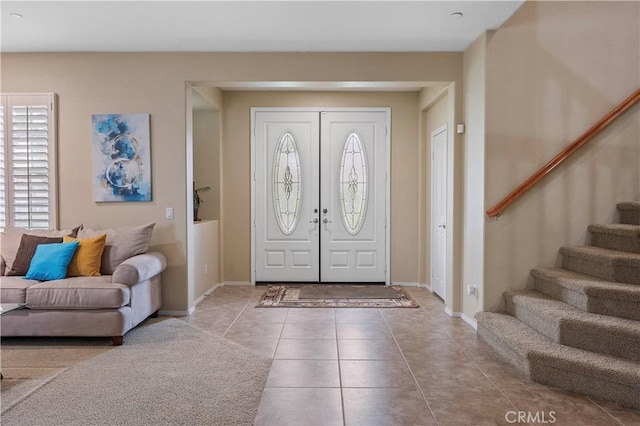 foyer with stairway, baseboards, and tile patterned flooring