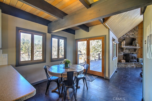 dining space with lofted ceiling with beams, a wood stove, and a wealth of natural light