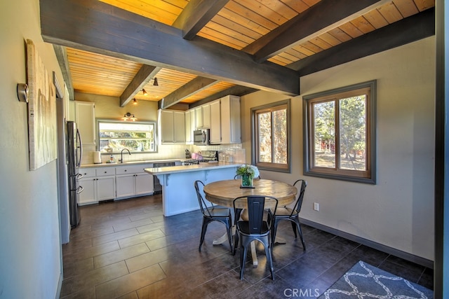 tiled dining room featuring wooden ceiling, beam ceiling, sink, and plenty of natural light