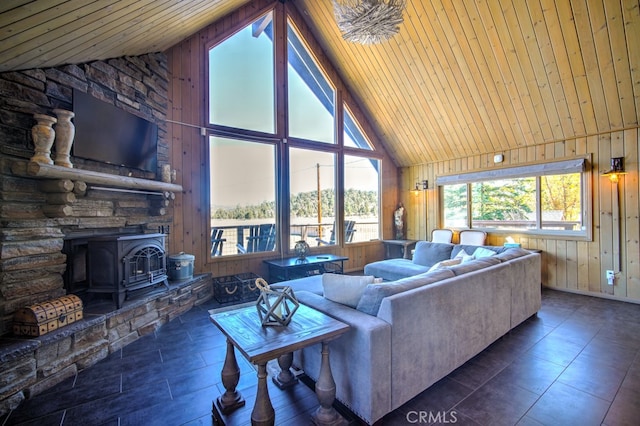 living room with high vaulted ceiling, a wood stove, wood walls, and wooden ceiling