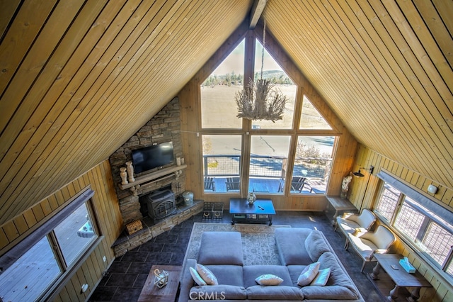 living room with wooden ceiling, a fireplace, wood walls, and high vaulted ceiling