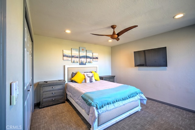 bedroom featuring a textured ceiling, dark colored carpet, ceiling fan, and a closet