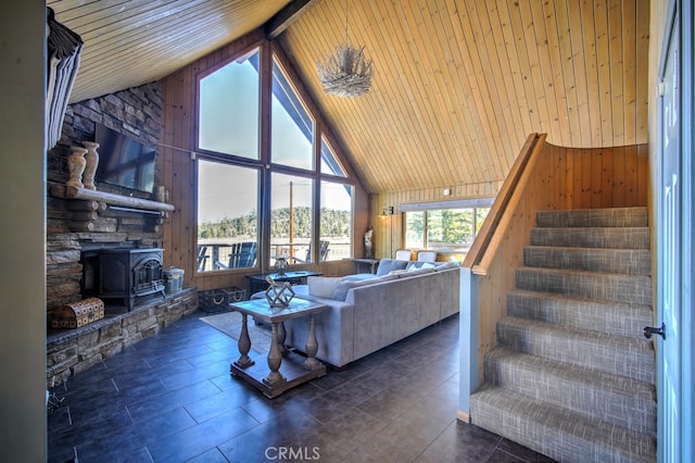 living room with wooden ceiling, wooden walls, a wood stove, and high vaulted ceiling