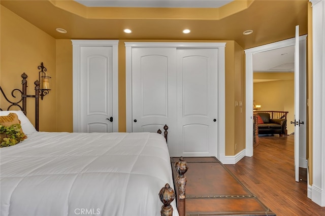 bedroom with a tray ceiling and dark hardwood / wood-style floors