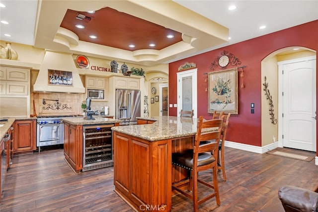 kitchen featuring a center island, dark hardwood / wood-style floors, beverage cooler, premium appliances, and premium range hood