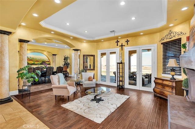 living area featuring a tray ceiling, hardwood / wood-style floors, french doors, and ornate columns