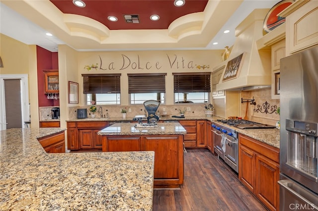 kitchen featuring a tray ceiling, a center island, appliances with stainless steel finishes, and backsplash