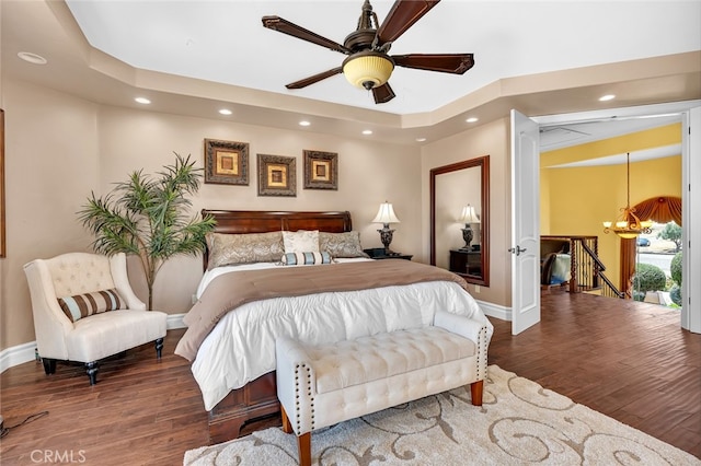 bedroom featuring wood-type flooring and ceiling fan with notable chandelier