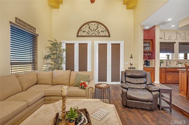 living room featuring a towering ceiling, dark hardwood / wood-style flooring, french doors, and plenty of natural light