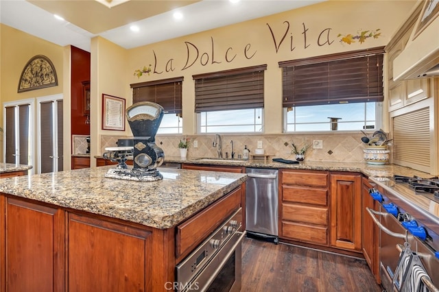 kitchen featuring light stone counters, dark hardwood / wood-style floors, sink, backsplash, and appliances with stainless steel finishes