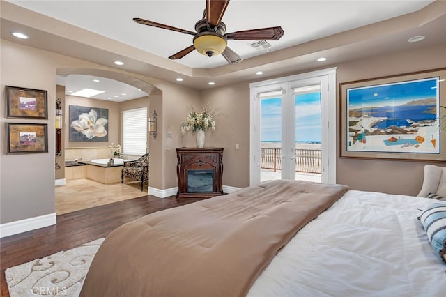 bedroom featuring access to outside, dark hardwood / wood-style flooring, ceiling fan, and french doors