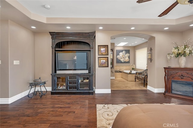 living room featuring ceiling fan and dark hardwood / wood-style flooring