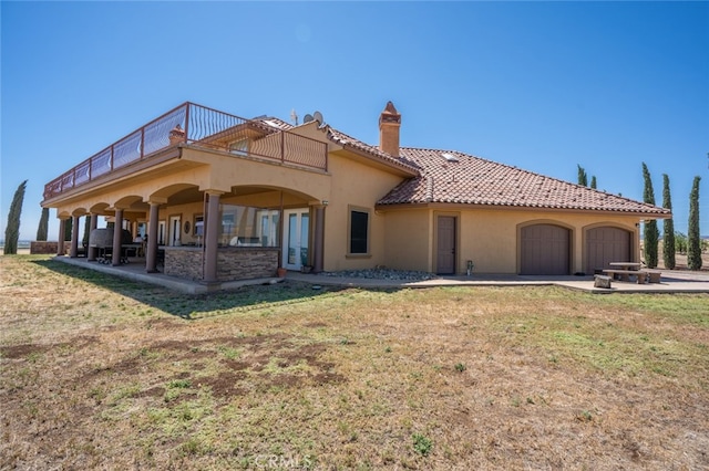 back of property featuring a yard, a balcony, and a patio area