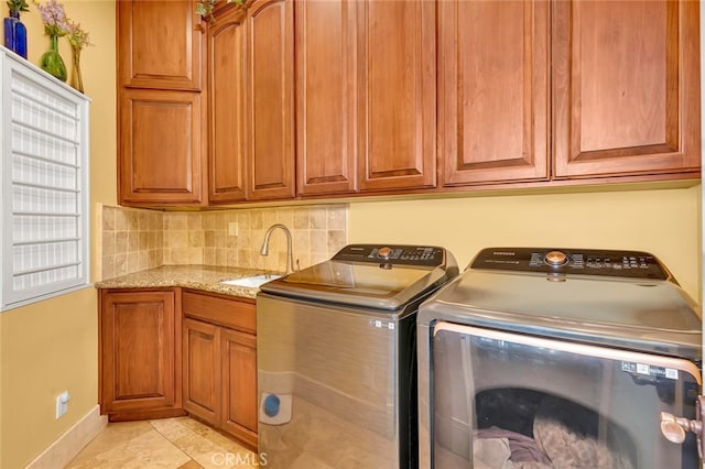 washroom with sink, washing machine and clothes dryer, and cabinets