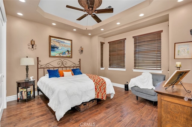 bedroom with ceiling fan, a raised ceiling, and dark hardwood / wood-style floors