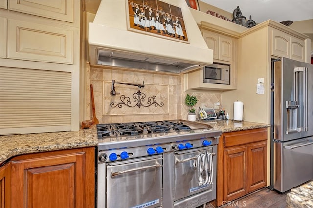 kitchen with light stone countertops, dark wood-type flooring, high end appliances, and tasteful backsplash