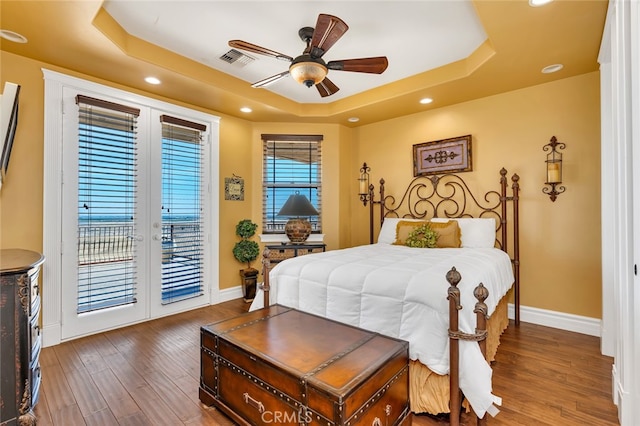 bedroom with access to outside, a tray ceiling, ceiling fan, and dark wood-type flooring