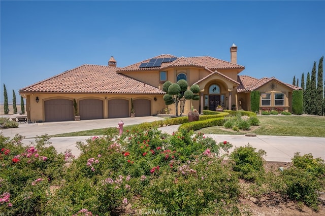 mediterranean / spanish-style house featuring a garage, solar panels, and a front yard