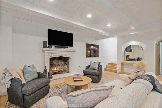 living room featuring light hardwood / wood-style flooring, a high end fireplace, and beamed ceiling