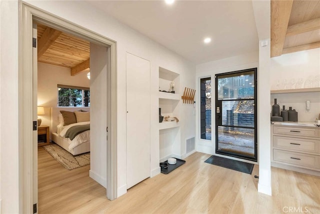 doorway to outside with beamed ceiling, wooden ceiling, and light hardwood / wood-style flooring