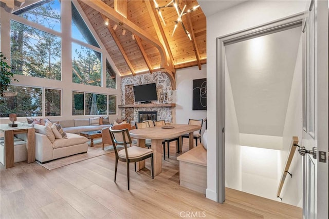 sunroom / solarium featuring a stone fireplace, vaulted ceiling with beams, and wooden ceiling