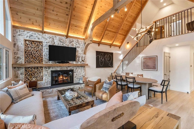 living room featuring hardwood / wood-style floors, wood ceiling, a stone fireplace, and a healthy amount of sunlight