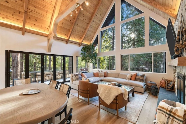 sunroom with vaulted ceiling with beams, a stone fireplace, plenty of natural light, and wooden ceiling