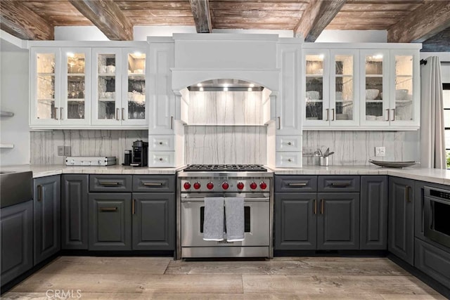 kitchen featuring beam ceiling, white cabinetry, and premium range