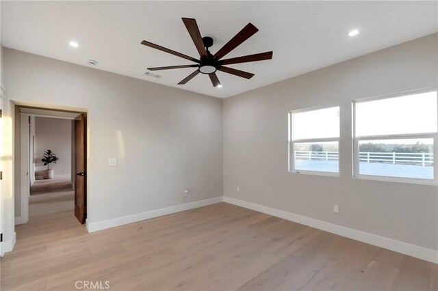 empty room with ceiling fan and light hardwood / wood-style flooring