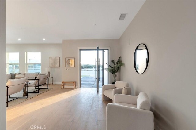 living room featuring light hardwood / wood-style floors, a water view, and a wealth of natural light