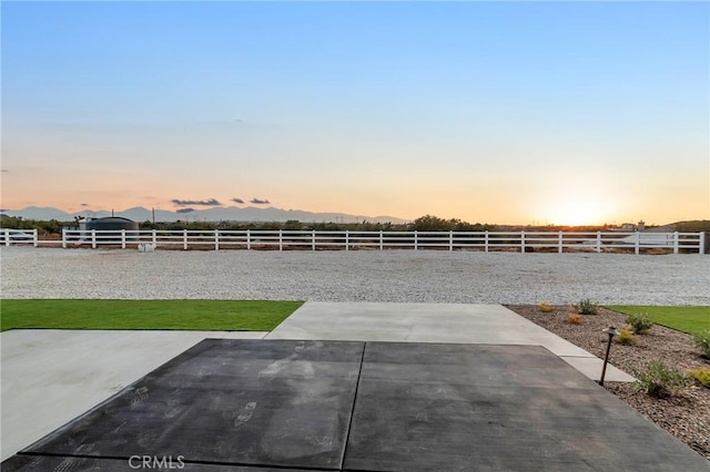 yard at dusk featuring a patio and a mountain view